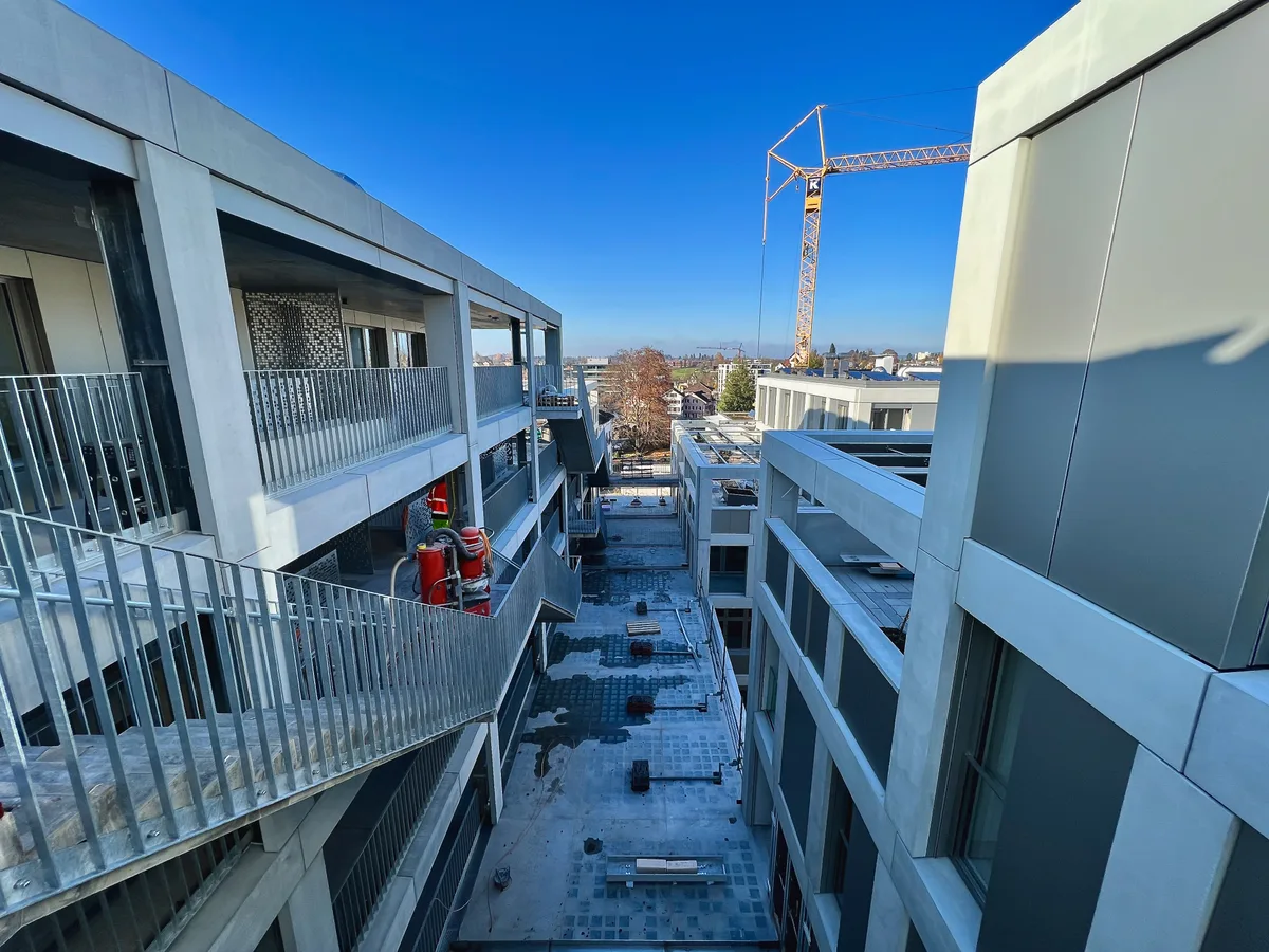 Es ist eine Kluft zwischen den Gebäudeteilen zu sehen. Auf der linken Seite verlaufen Treppen entlang des Gebäudes.